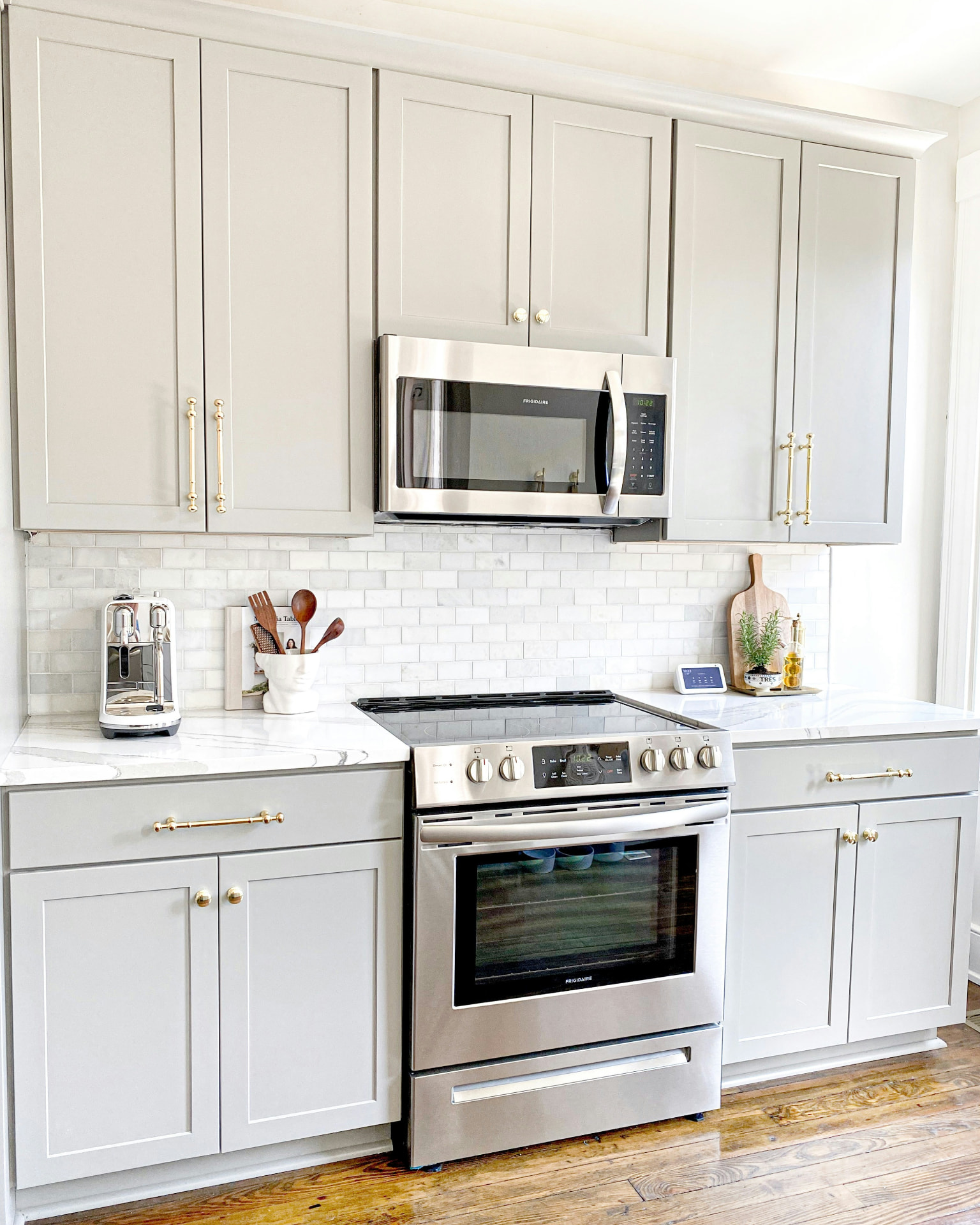 Freshly painted light-gray shaker kitchen cabinets with brass hardware