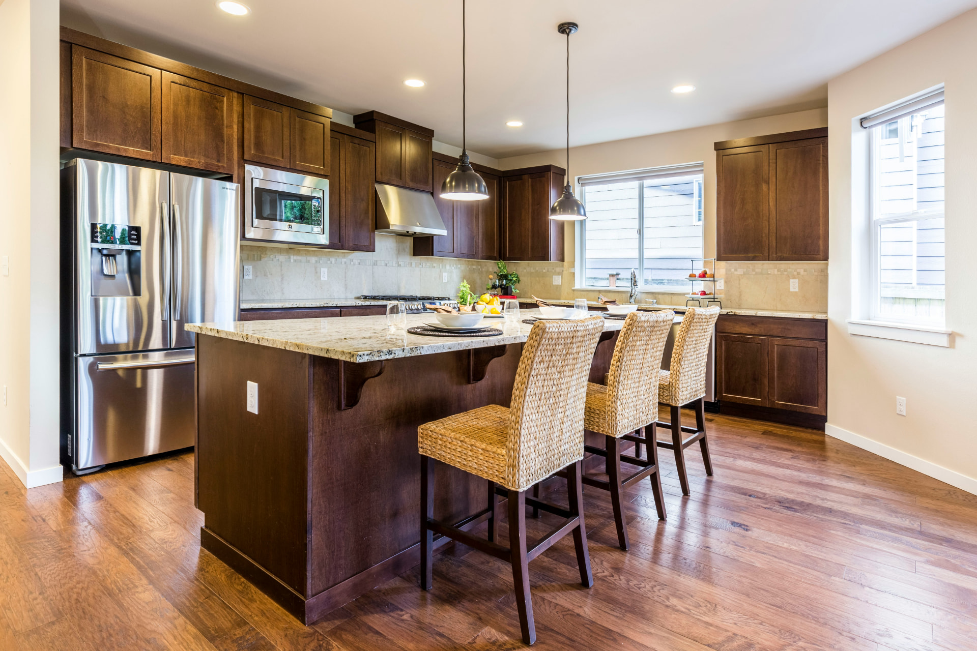 Kitchen with richly stained walnut cabinets, granite countertops, and a large island with bar seating