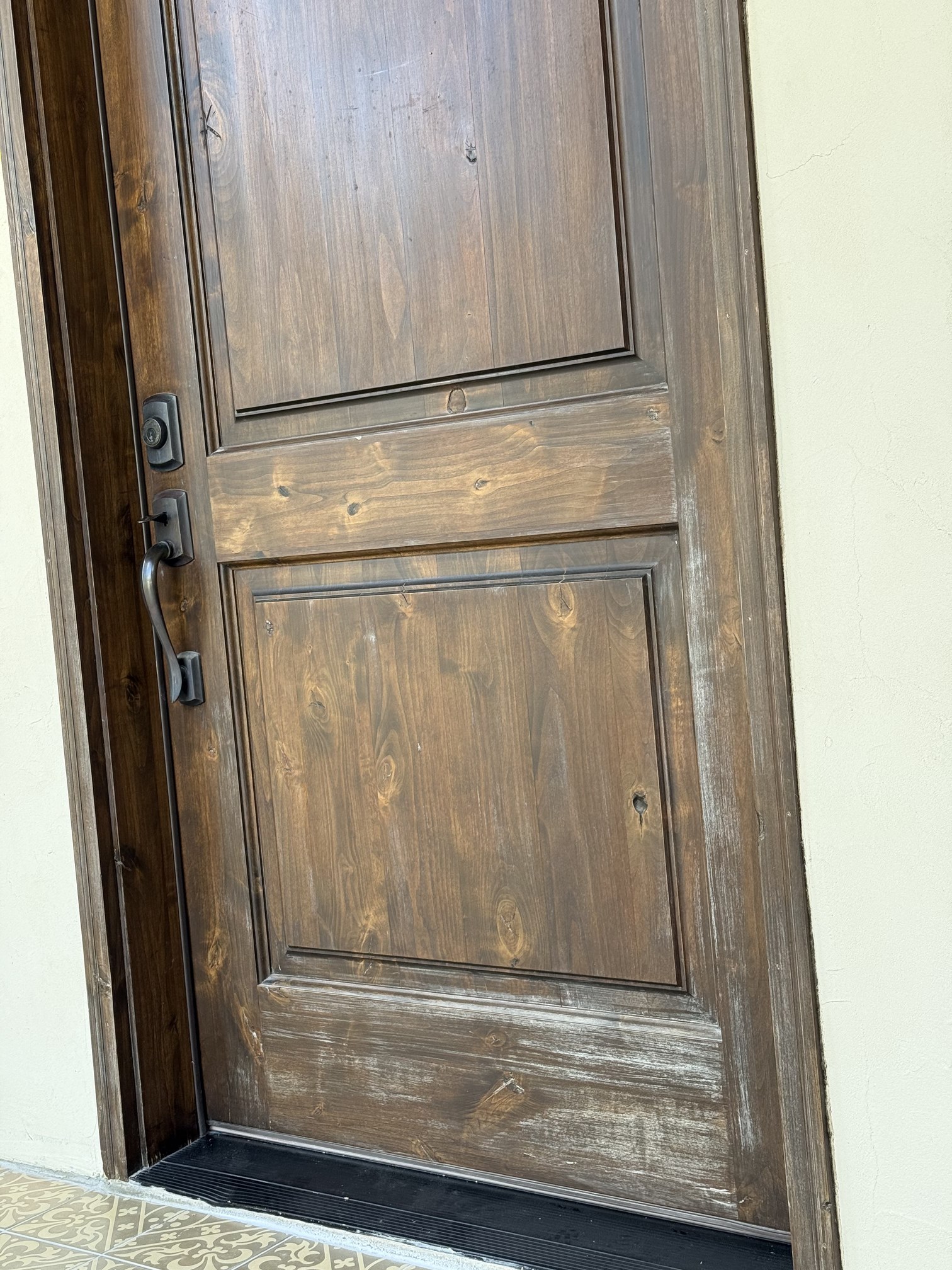 Worn dark-stained entry door with faded, scuffed finish before refinishing in New Braunfels