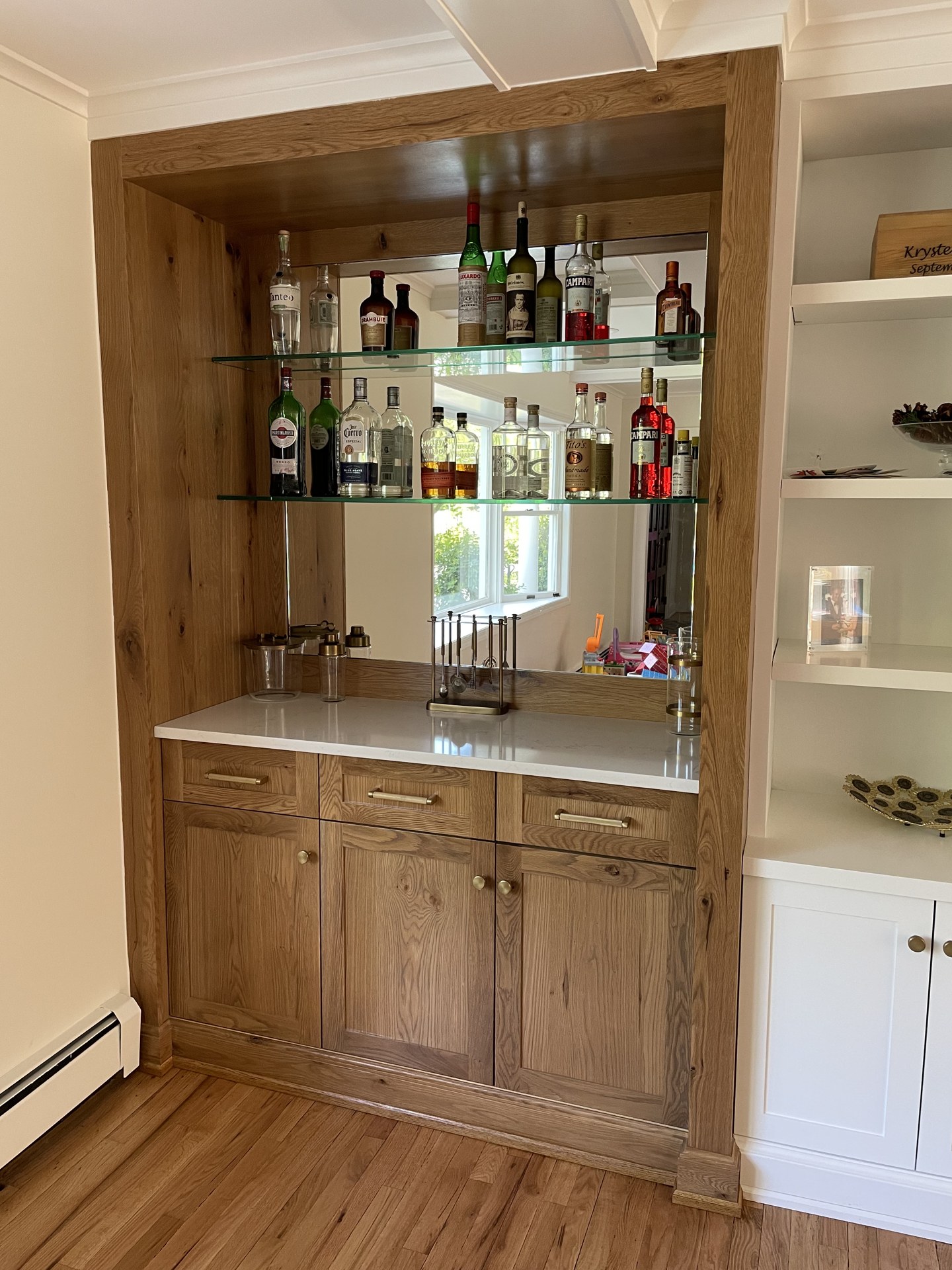 Finished white oak bar with glass shelves, mirrored back, and a warm even stain after refinishing in Austin