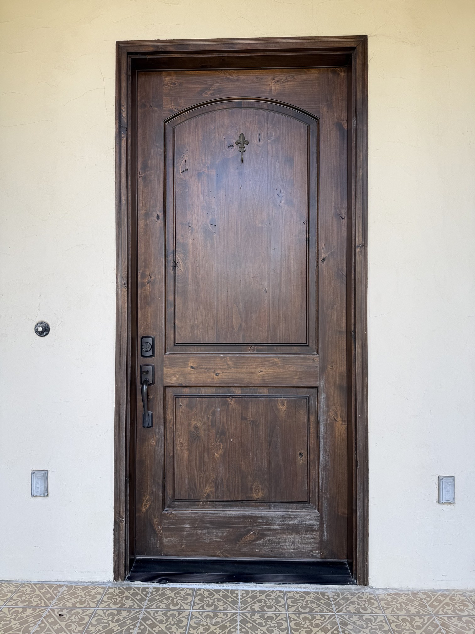 Sun-weathered wood entry door with a scuffed, worn lower panel before refinishing in New Braunfels