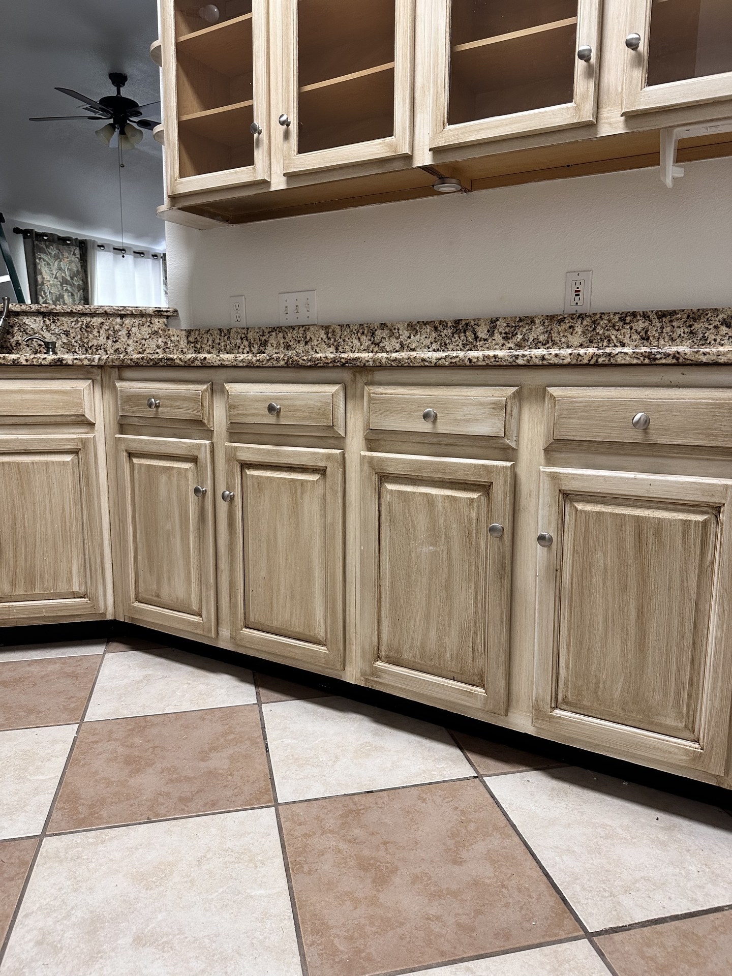 Worn beige cabinet drawers and lower cabinets with tile floor before painting in Austin