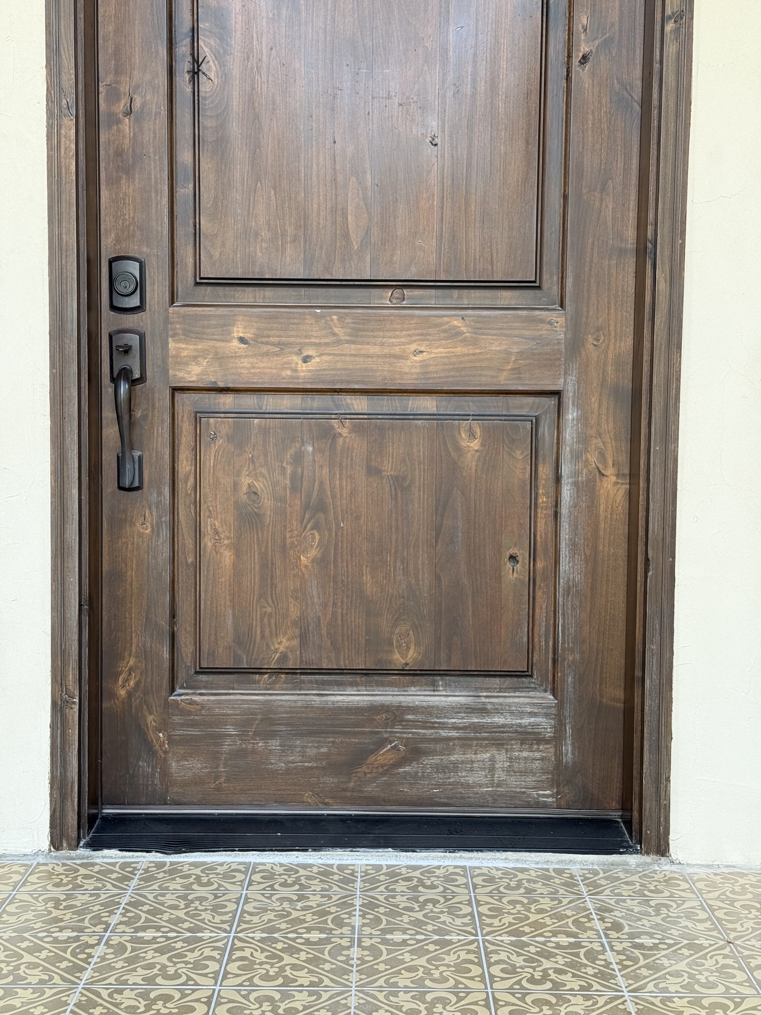 Full view of the weathered wood entry door with a scuffed, worn lower panel before refinishing in New Braunfels