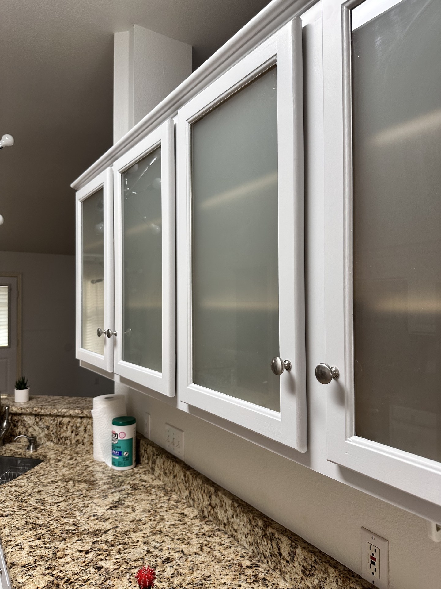 Glass-front upper cabinets painted a smooth bright white after refinishing in Austin