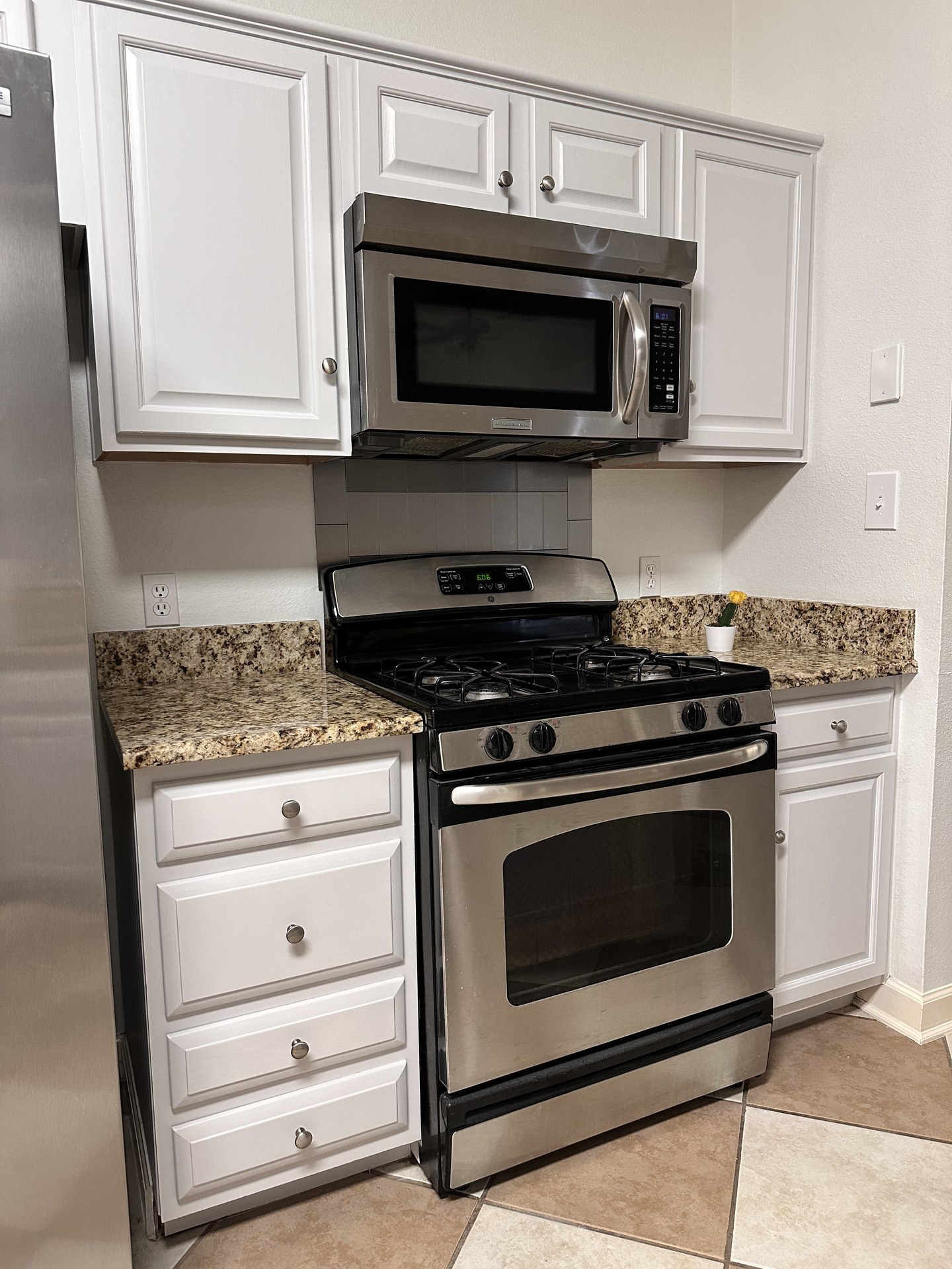 White painted cabinets around the stainless range and microwave after refinishing in Austin